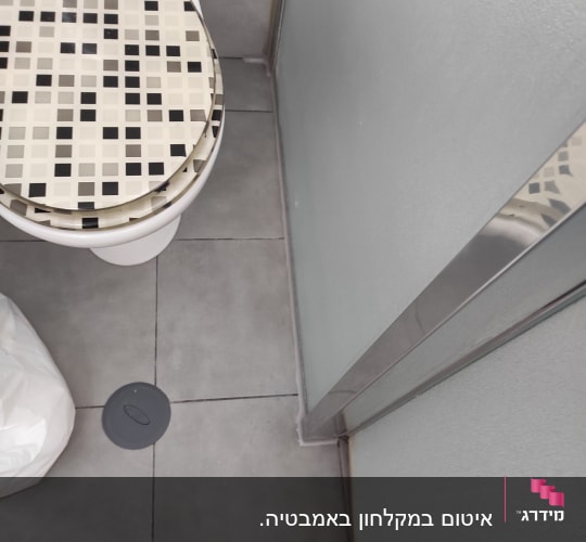 אסלה עם מושב מעוצב, רצפת אריחים, ניקוז עגול